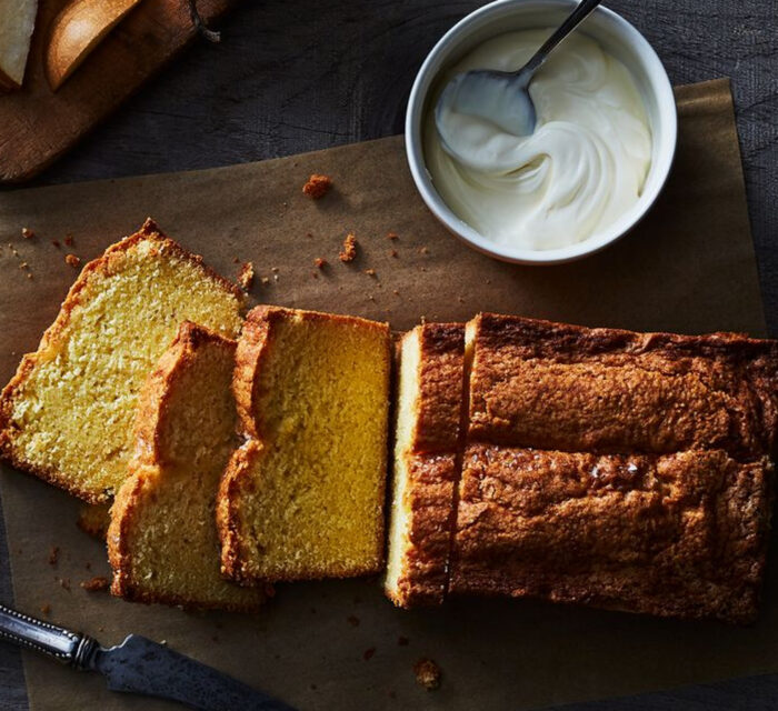 cake découpé sur une planche en bois avec un pot de yaourt à côté