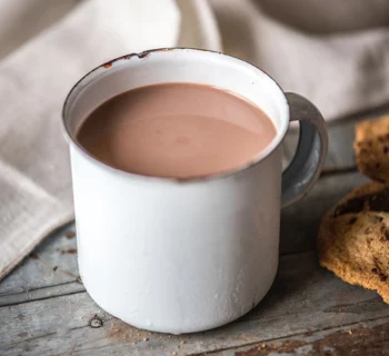 Chocolat chaud dans une tasse blanche sur une table avec des cookies à côté