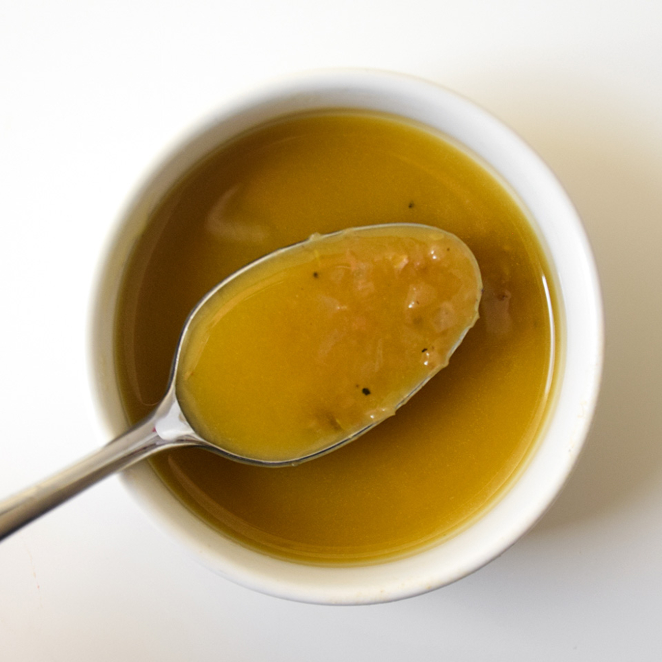 vinaigrette à la moutarde dans un bol blanc avec une cuillère en métal