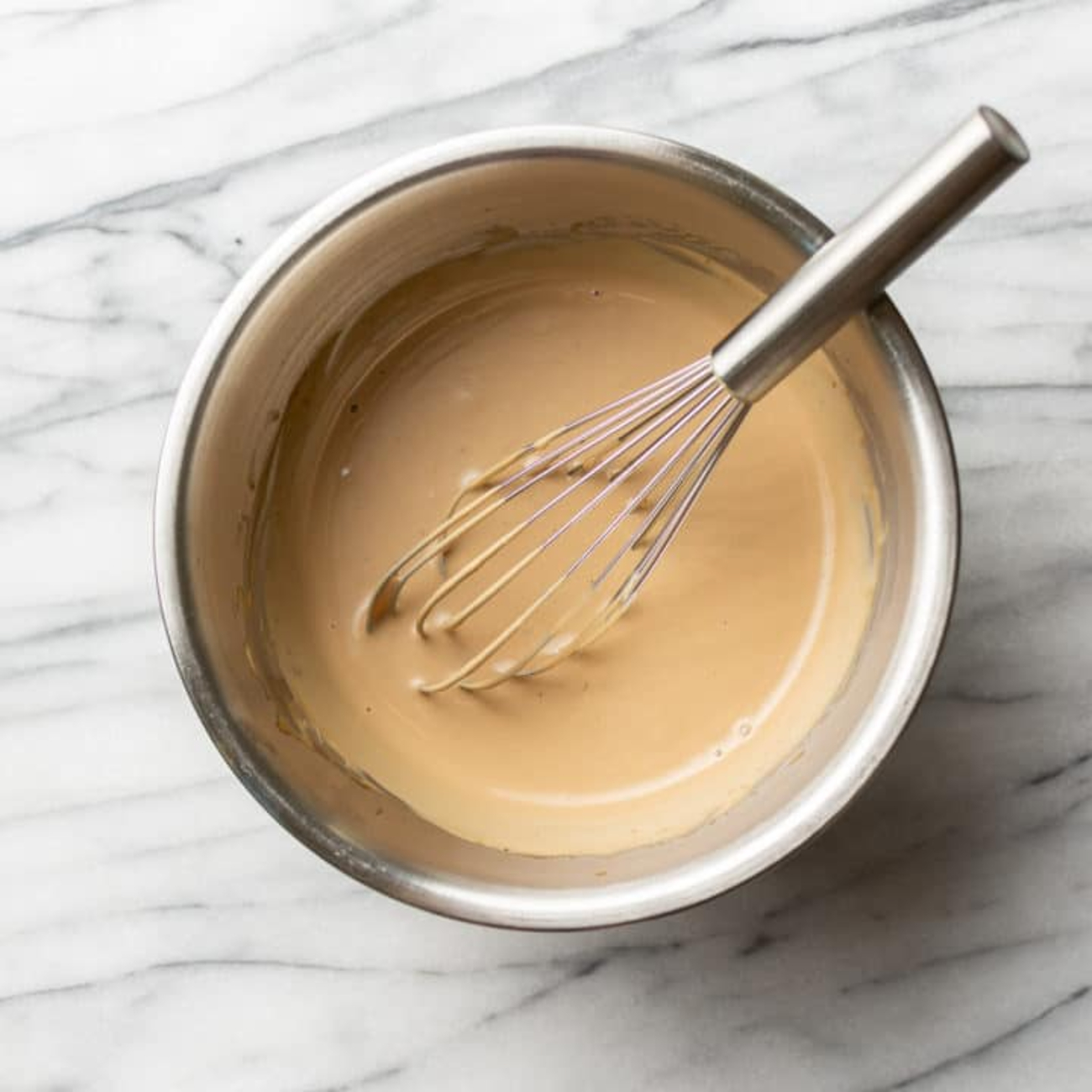 la vinaigrette beige avec du tahini dans un bol avec un fouet