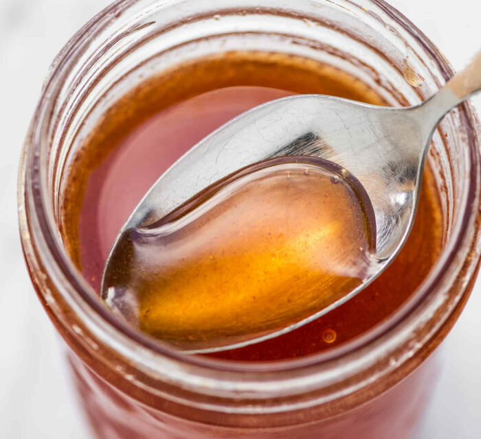 vinaigrette au miel avec une cuillère qui plonge dans le pot
